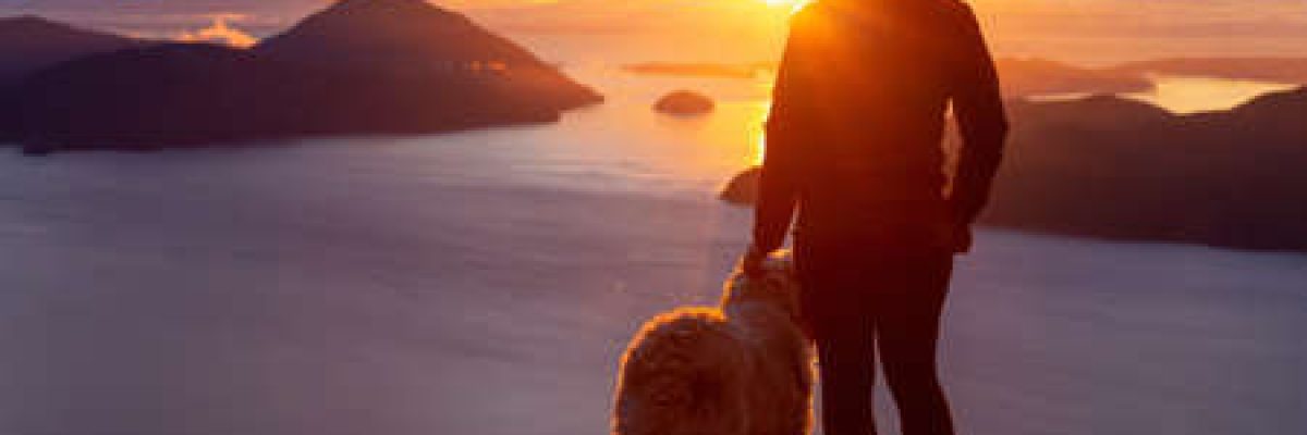 136168166-adventurous-girl-hiking-on-top-of-a-mountain-with-a-dog-during-a-colorful-sunset-taken-on-tunnel-blu